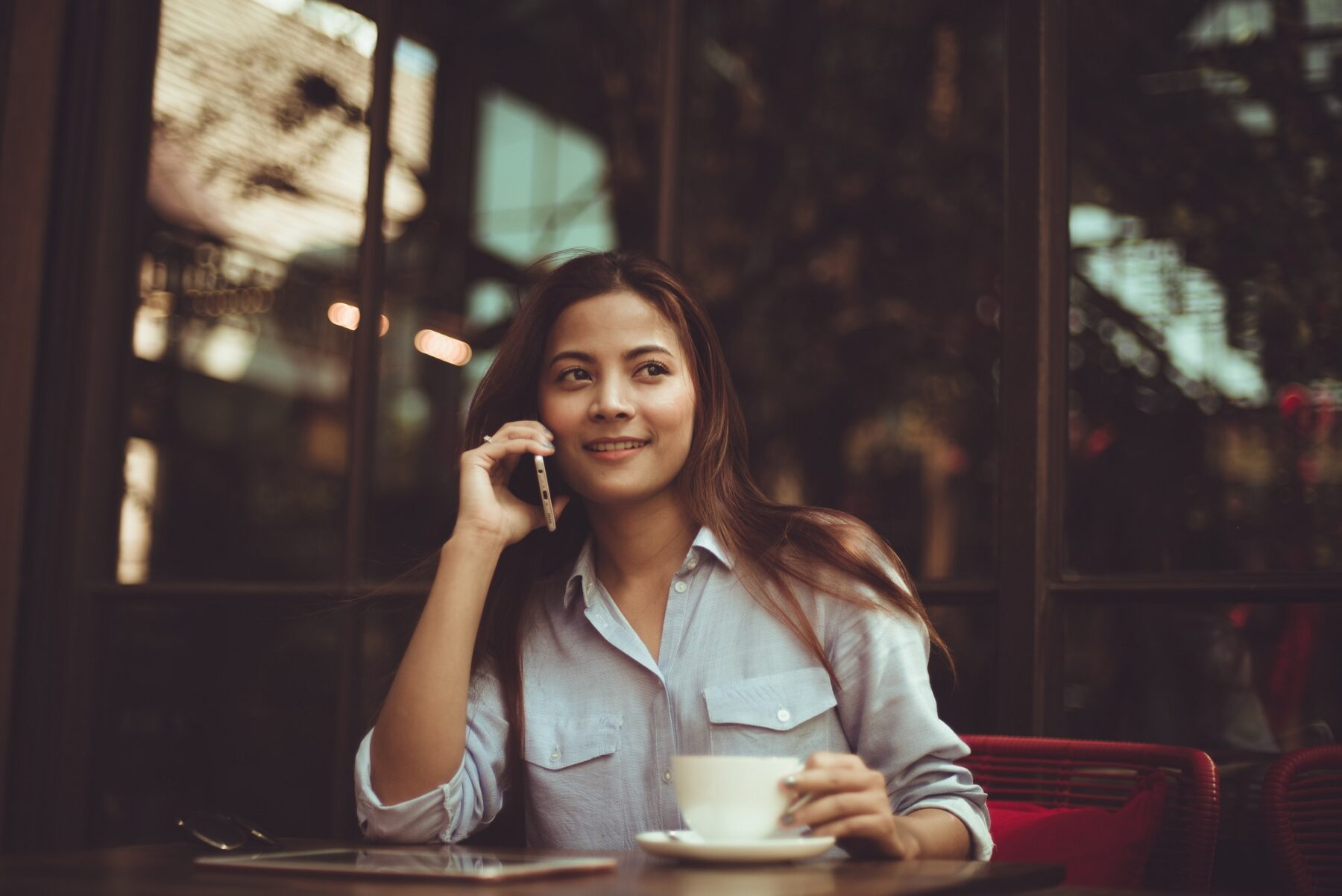 Woman sitting outside a cafe using a phone