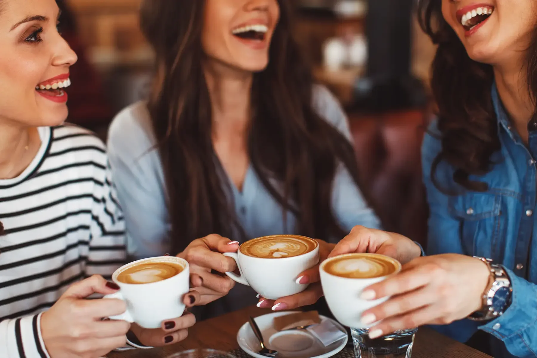 Group of young women with coffee drink smiling and laughing in a cafe