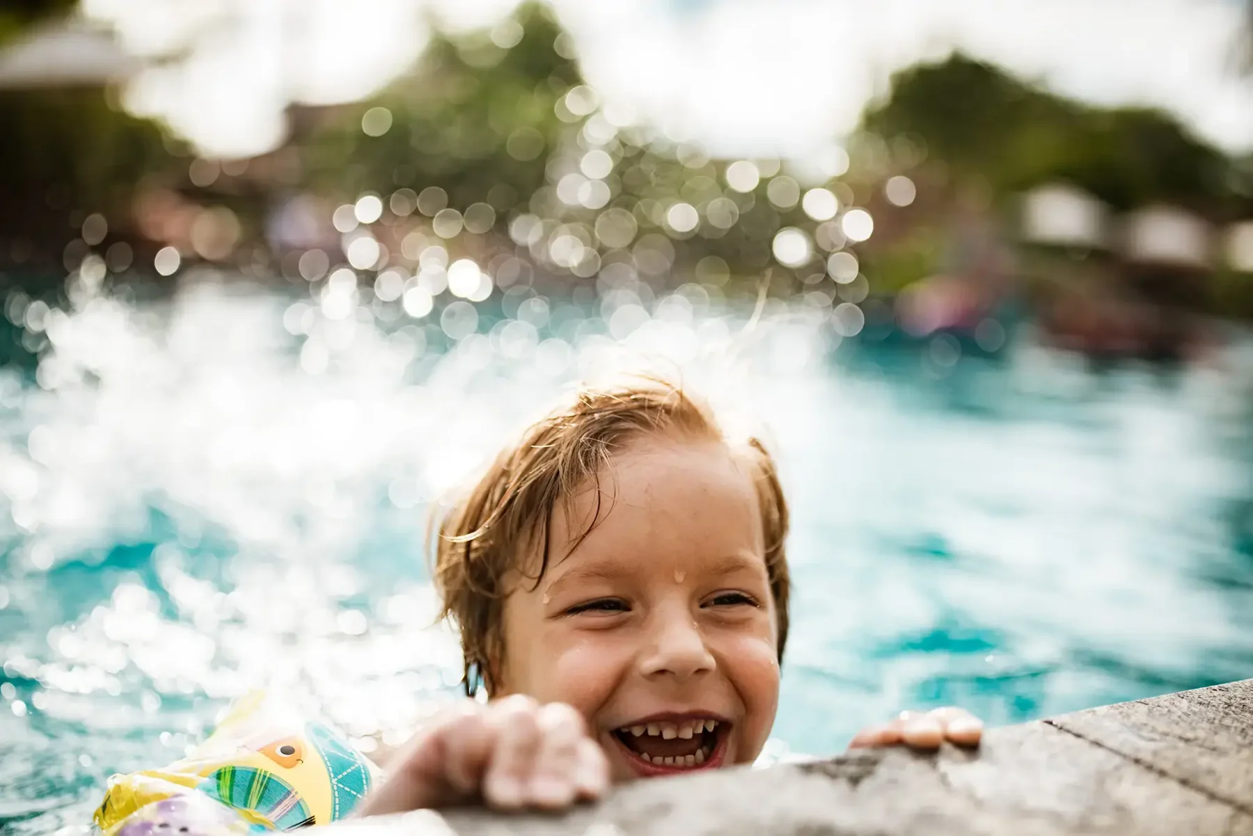 Young boy smiling and climbing out of a pool